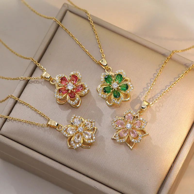 Four gold-plated rotatable flower necklaces with zirconia centerpieces in red, green, clear, and pink.